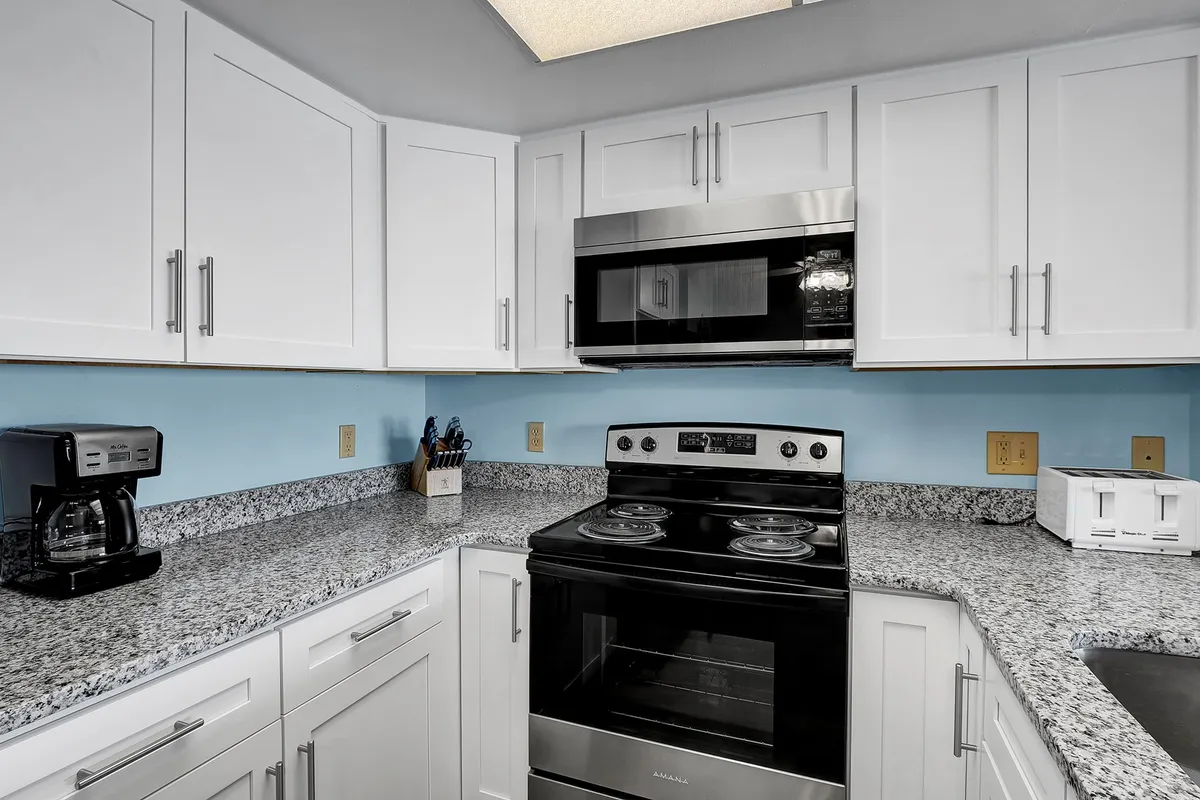 The image spotlights a contemporary kitchen with expansive granite countertops, stainless steel appliances, and ample cabinetry. The scene is set for cooking, baking, and hosting family or friends, reflecting a welcoming and functional culinary hub.