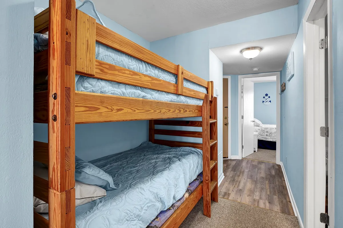 A playful bunk alcove featuring built-in bunk beds with blue walls and a hallway leading to other rooms. The space is designed with children in mind, perfect for shared sleepovers or quiet bedtime routines.